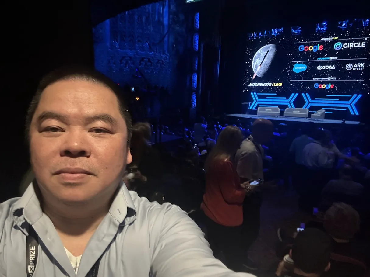 Ken in his seat before the program, with the sponsor screen behind him